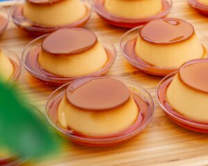 Close-up of smooth caramel flan arranged on wooden table.