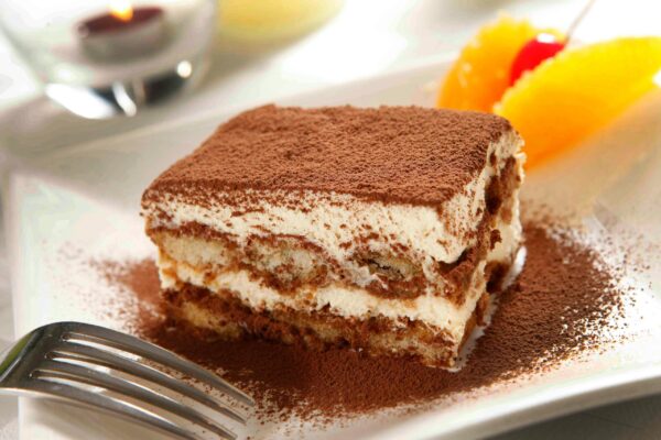 A close-up of a delicious tiramisu dessert dusted with cocoa powder, ready to enjoy.